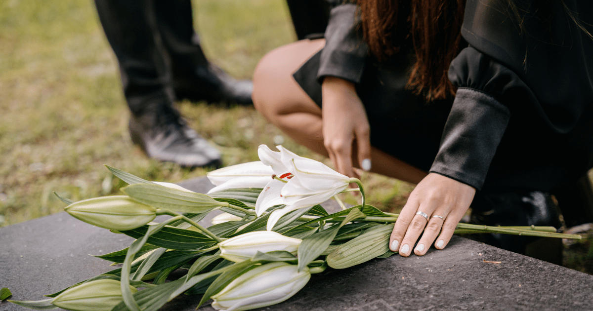 Woman laying flowers down on a coffin at a funeral