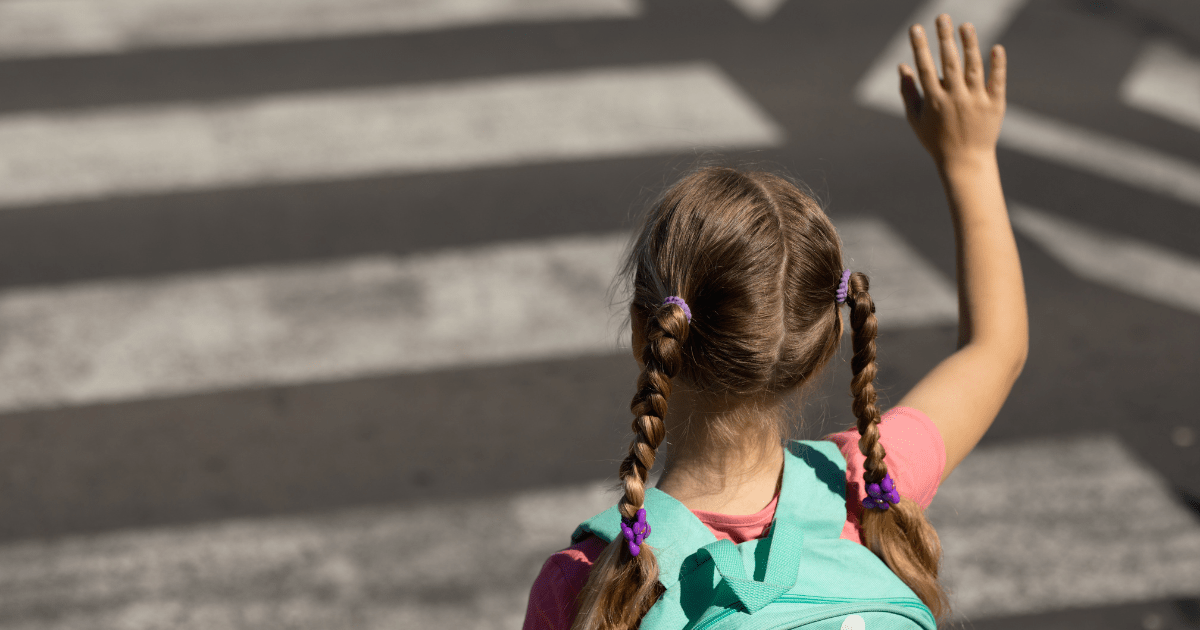 pedestrian waving as she crosses a crosswalk