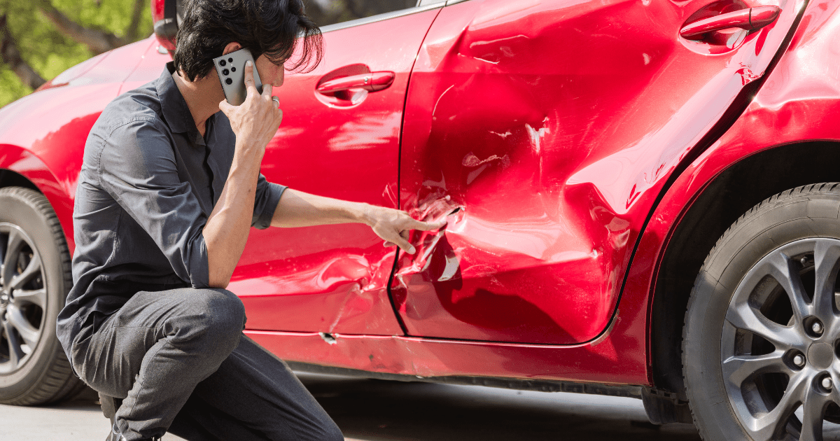 man inspecting his car to see what he should do after a car accident